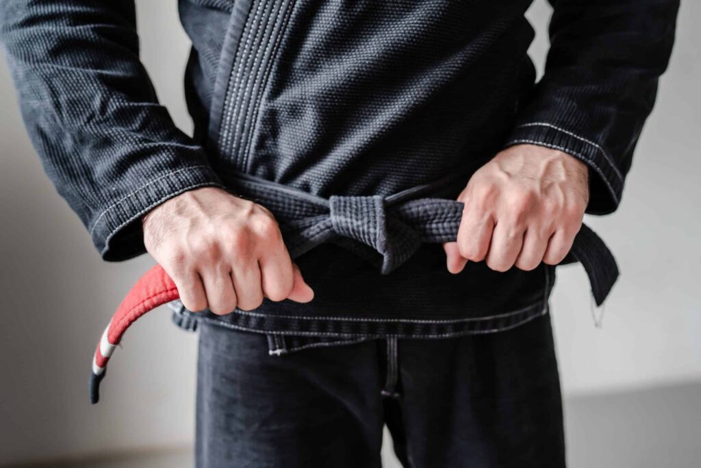 Person knyter BJJ-belte på svart gi – brasiliansk jiu-jitsu belte rekkefølge