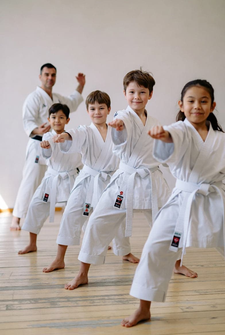 Barn i hvit karate-gi øver slag med instruktør – karate for barn
